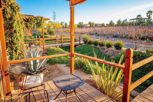 A wooden deck with a pergola, two chairs, and a table.