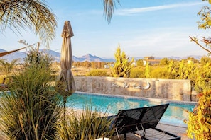 A pool area with a chair and a stone wall with a crescent moon design.
