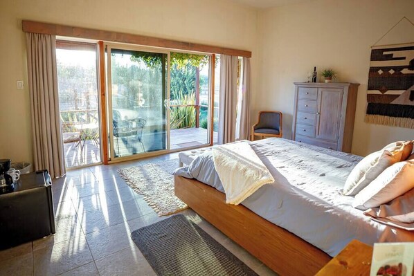 Un dormitorio con una cama grande, una puerta corrediza al balcón, un escritorio pequeño y un armario.