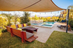 Un patio al aire libre con piscina, zona de estar y una pérgola que proporciona sombra.