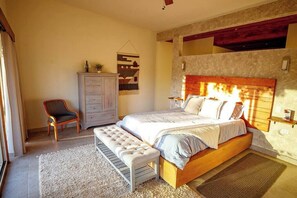 Un dormitorio con cama, un banco, un aparador y una estantería en la pared.