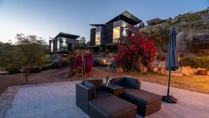 A modern house with a patio area featuring wicker furniture and a large umbrella.