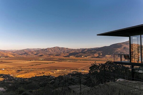 A modern building with a glass facade overlooking a mountainous landscape.