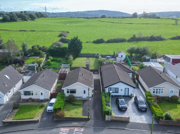 A residential area with houses, a green field, and a clear sky.