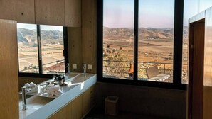 A modern bathroom with a large window, a sink, and a bench.