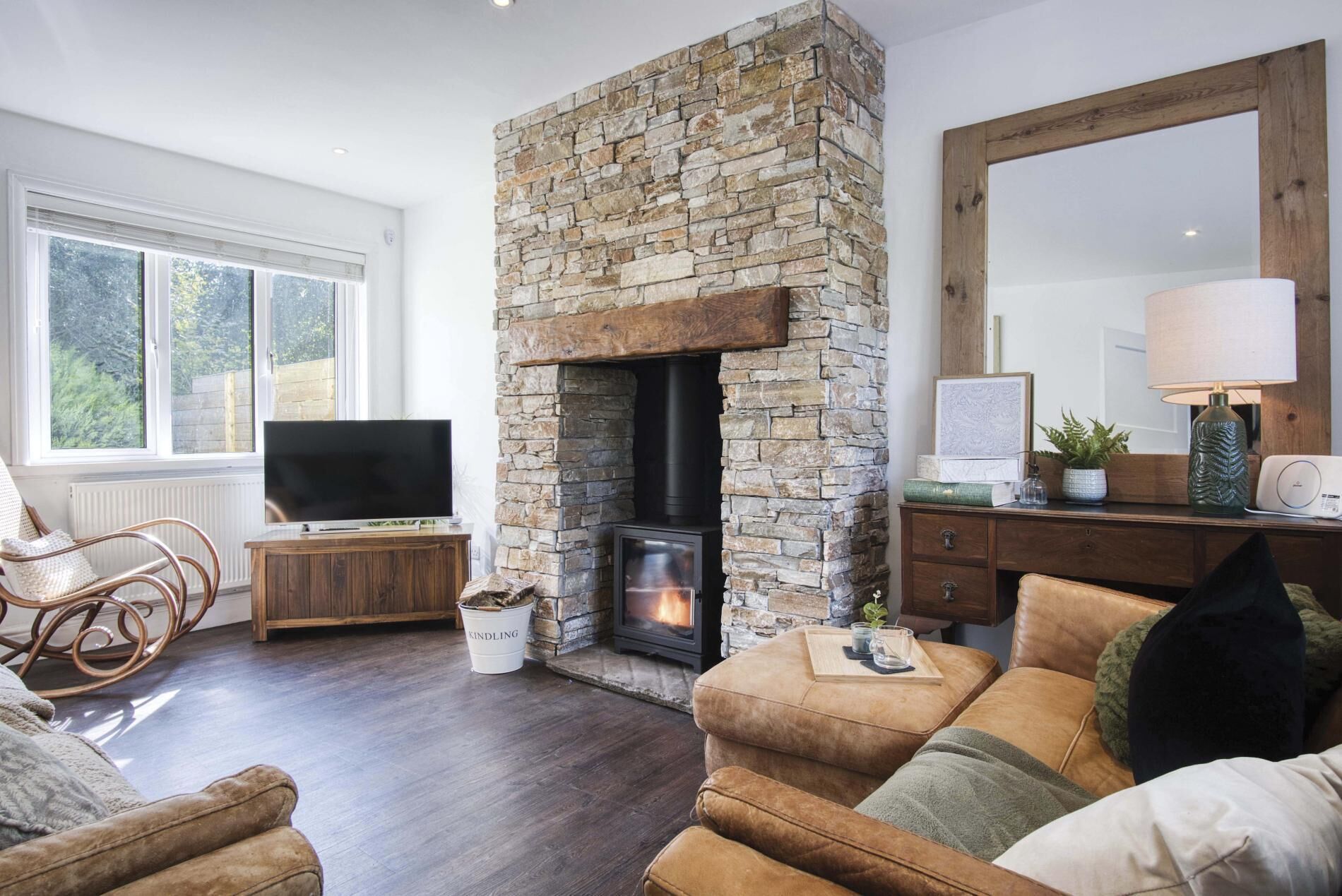 A cozy living room with a stone fireplace, a television, and comfortable seating.