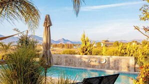 A pool area with a chair and a stone wall with a crescent moon design. - Vinyard Cabin - Luna del Valle (Valle de Guadalupe)