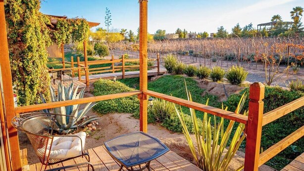 A wooden deck with a pergola, two chairs, and a table. - Vinyard Cabin - Luna del Valle (Valle de Guadalupe)