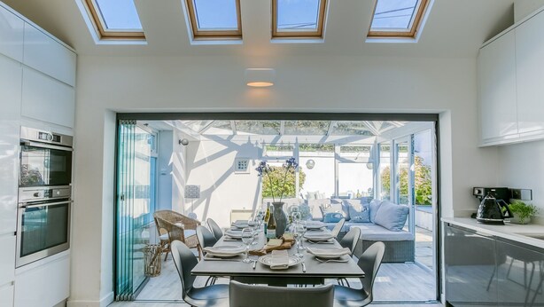 A modern kitchen with a dining area, large windows, and a view of the garden. - Ty Haf - sleeps 9 guests  in 5 bedrooms (Rhosneigr)