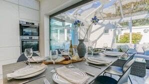 A dining area with a table set for four, a Bosch oven, and a glass partition. - Ty Haf - sleeps 9 guests  in 5 bedrooms (Rhosneigr)