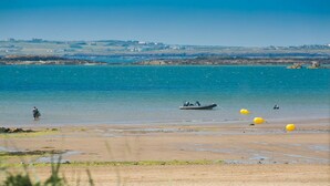 A beach with a boat, yellow buoys, and a person standing in the water. - Ty Haf - sleeps 9 guests  in 5 bedrooms (Rhosneigr)