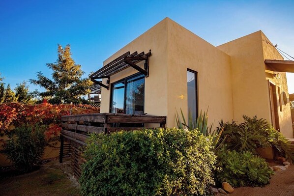 A modern house with a wooden deck, large windows, and a well-maintained garden.