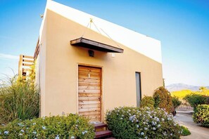 A modern building with a beige exterior, a wooden door with a number '1', and a small window to the right.