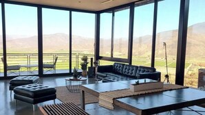 Un salón amplio con un ventanal grande que ofrece vistas a un paisaje verde y montañas.