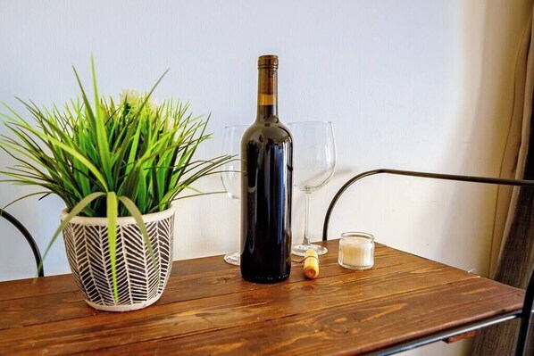 Una mesa de madera con una planta en maceta, una botella de vino, una copa y una vela.
