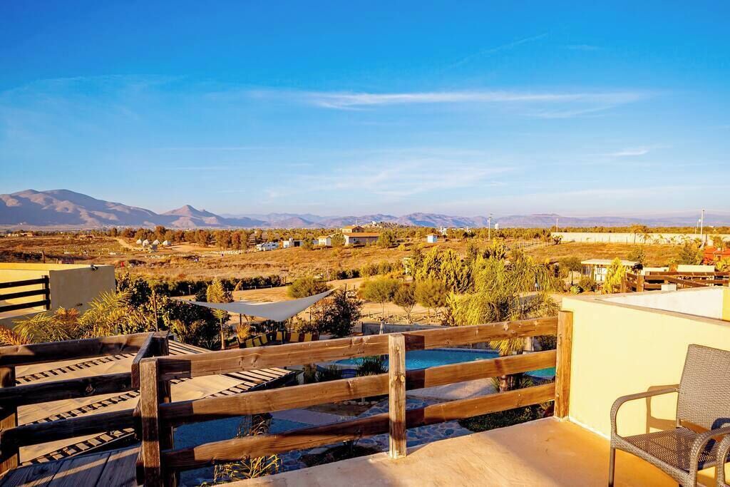 A rooftop terrace with a wooden fence, a pool, and a view of distant mountains.
