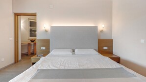 A bedroom with a large bed, bedside lamps, a wooden headboard, and a small table with a bowl. - Apartment 'Landhaus Antonius Loft Suite Vitus' with Mountain View, Wi-Fi and Air Conditioning (St. Michael Eppan)