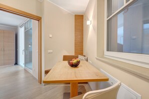 Un comedor con una mesa de madera, un cuenco de fruta y una ventana.