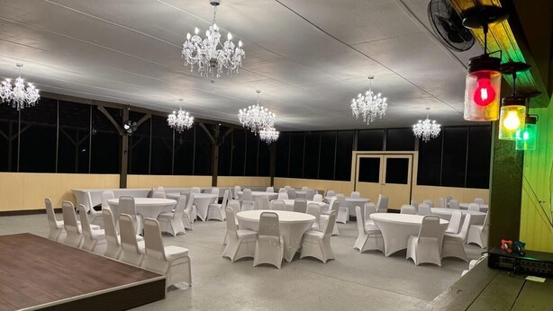A banquet hall with round tables and chairs, chandeliers, and a stage.