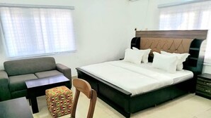 A bedroom with a bed, a sofa, a small table, and a chair. - Oak Up Ultimate Place  (Abuja)