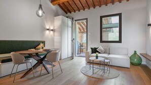 A modern living room with a dining area, featuring a wooden ceiling, a white sofa, a round coffee table, and a dining table with chairs.