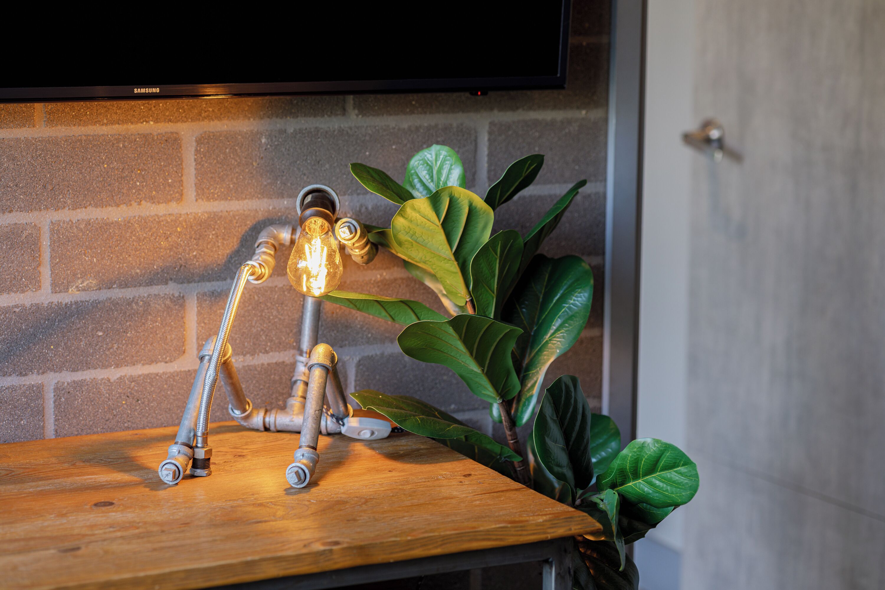 Une table en bois, ornée d’un robinet en métal original, et une plante en pot placée à côté.