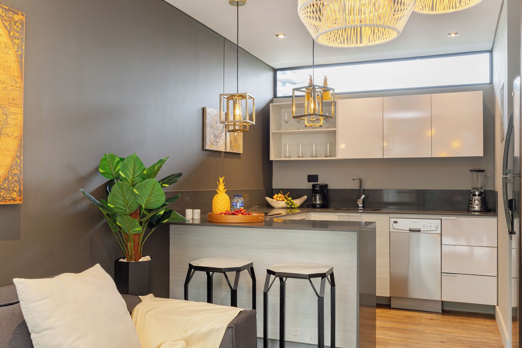 A modern kitchen with a central island, bar stools, a coffee machine, and a dishwasher.
