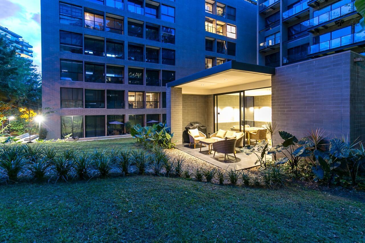 A modern building with a courtyard featuring outdoor seating and a well-maintained garden.