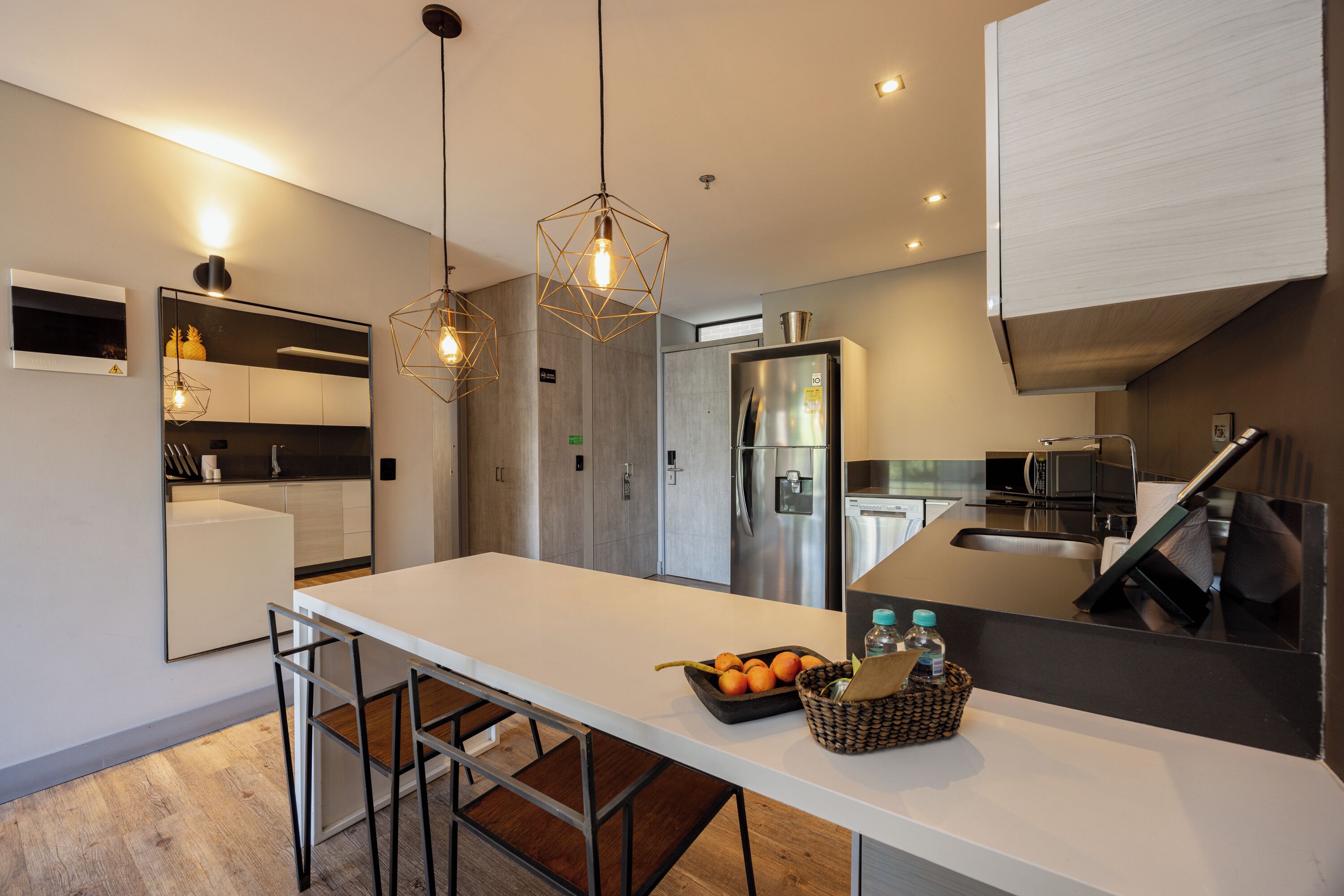 Una cocina moderna con encimera blanca, electrodomésticos de acero inoxidable y una isla grande con asientos.
