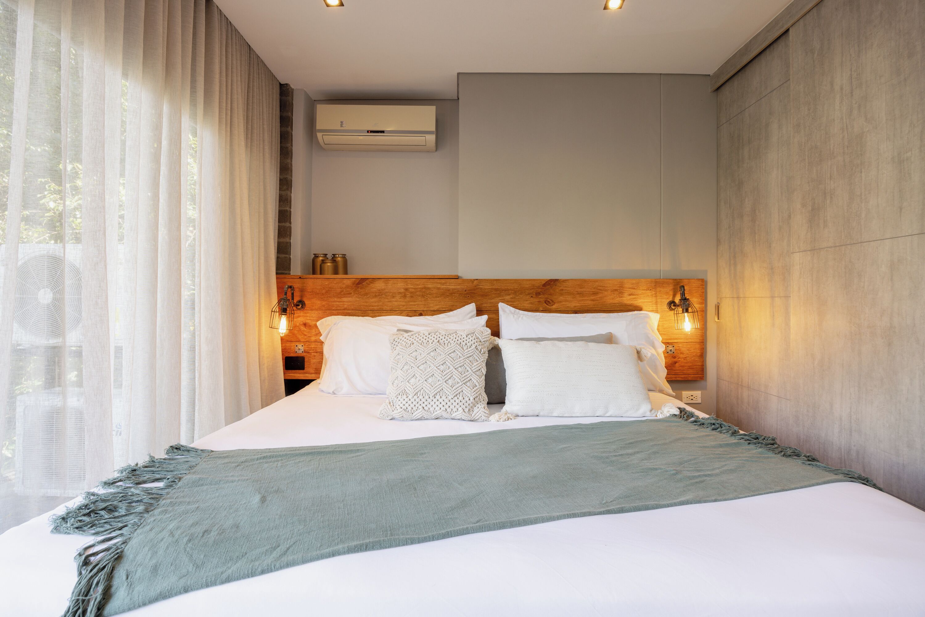 Un dormitorio moderno con una cama grande, cabecera de madera y lámparas de noche.