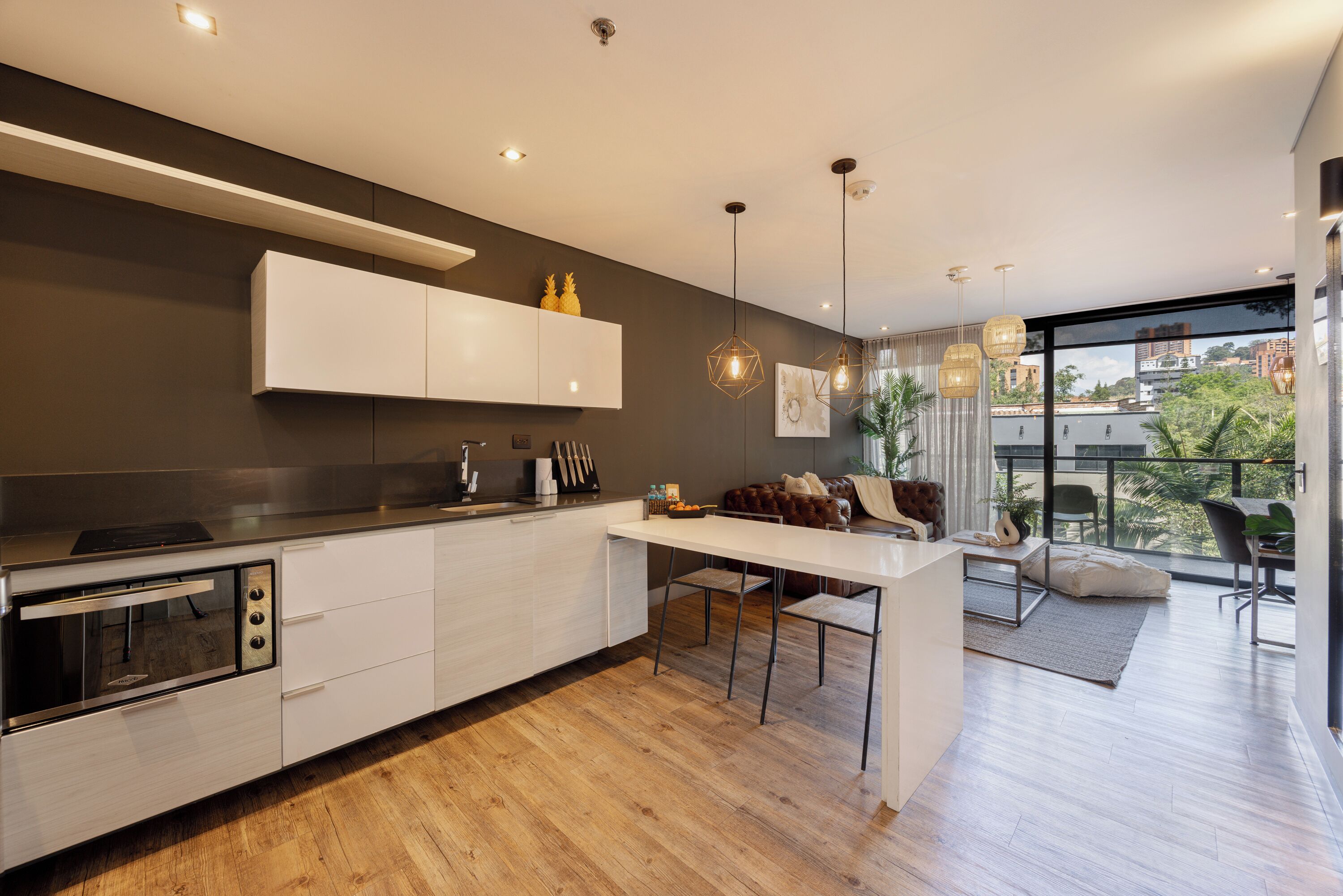 A modern kitchen with white cabinetry, a built-in oven, and a dining area with a white table and chairs.