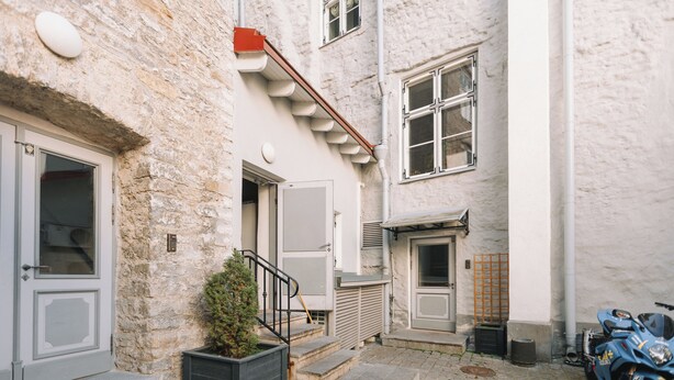 A narrow street with a stone building, a small staircase, and a parked motorcycle.
