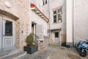 A narrow street with a stone building, a small staircase, and a parked motorcycle. - DICTUMFACTUM Sky Apartment — Your Perfect Stay in the Heart of Tallinn! (Tallinn)