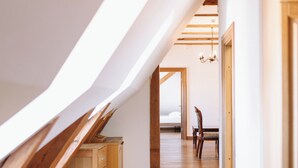 An attic room with wooden flooring, a dining table, and chairs.