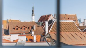 A view of a cityscape with various buildings, including a prominent church tower and residential structures with red-tiled roofs.