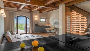 Een modern interieur met een houten plafond, een eethoek met een zwarte tafel en een wijnrek.