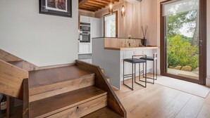 Een moderne keuken met witte kasten, een houten trap en uitzicht op de omgeving.