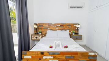 A neatly made bed with a wooden headboard, two bedside tables with lamps, and a white wardrobe.