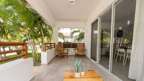 Un espace extérieur aménagé, abrité et doté de mobilier en bois et de plantes en pot.