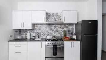 A modern kitchen with white cabinets, a black refrigerator, and a patterned backsplash.