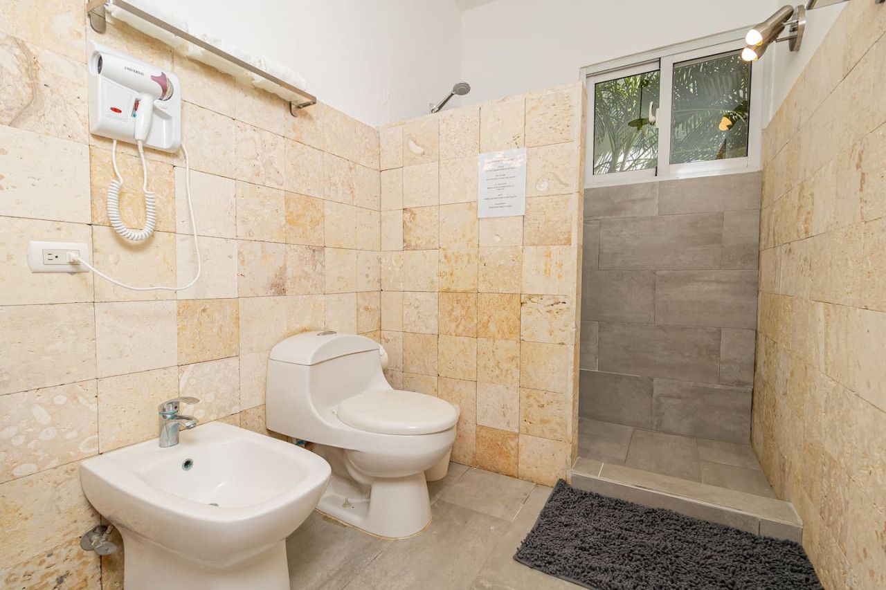 Een badkamer met twee toiletten, een bidet, een haardroger en een douche.