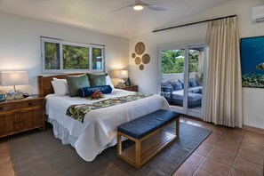 Un dormitorio con cama, mesitas de noche, un banco, una ventana y vistas al exterior.