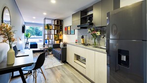 A modern kitchen with a built-in refrigerator, a dining area with a laptop, and a seating area with a sofa and coffee table. - Comfortable Loft in Zona T w/ Fast Wi-fi (BOGOTA)