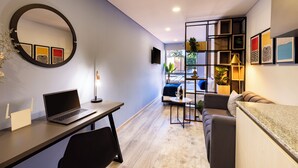 A modern living room with a laptop on a desk, a sofa, a coffee table, and a TV mounted on the wall. - Comfortable Loft in Zona T w/ Fast Wi-fi (BOGOTA)