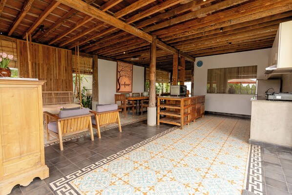 A spacious room with a tiled floor, wooden furniture, and a kitchen area.