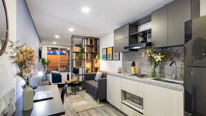 A modern kitchen with a built-in oven, a sink, and a coffee maker. There is a dining area with a table and chairs, and a sofa. - Exclusive Loft w/ Terrace In Zona T w/ Fast Wi-Fi (BOGOTA)