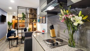 A modern kitchen with a built-in stove, a dining area with a sofa and a small table, and a decorative plant arrangement. - Exclusive Loft w/ Terrace In Zona T w/ Fast Wi-Fi (BOGOTA)