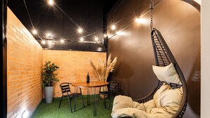 A cozy indoor seating area with a hanging chair, a round table, and chairs. There is a potted plant and a bottle on the table. - Exclusive Loft w/ Terrace In Zona T w/ Fast Wi-Fi (BOGOTA)