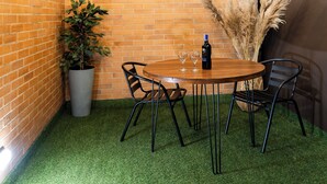 A corner room with a brick wall, a wooden table with chairs, a potted plant, and pampas grass. - Exclusive Loft w/ Terrace In Zona T w/ Fast Wi-Fi (BOGOTA)