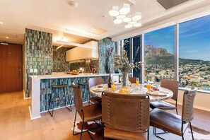 Une cuisine moderne avec un coin bar, une table à manger avec des chaises et une grande fenêtre donnant sur la ville.